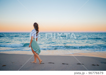 Happy woman enjoying beautiful sunset on the beach 96776679