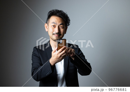 スマホを持つ髭の男性 96776681