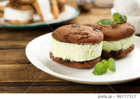 Sweet delicious ice cream cookie sandwiches on wooden table 96777317