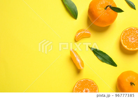 Flat lay composition with fresh ripe tangerines and leaves on yellow background, space for text. Citrus fruit 96777385