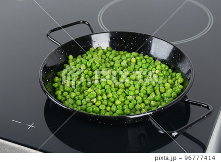 Cooking frozen sweet peas on induction stove. Vegetable preservation Cooking frozen sweet peas on induction stove. Vegetable preservation 96777414