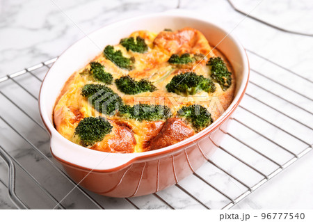 Tasty broccoli casserole in baking dish on cooling rack, closeup 96777540