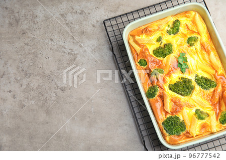 Tasty broccoli casserole in baking dish on cooling rack, top view. Space for text 96777542