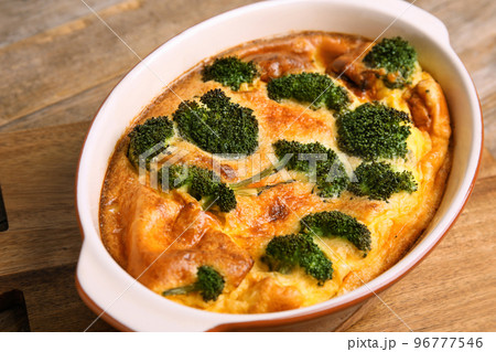 Tasty broccoli casserole in baking dish on wooden board, closeup 96777546