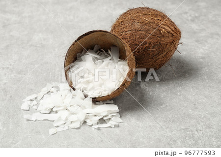 Tasty coconut chips and shell on grey table 96777593