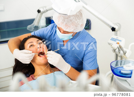 Dentist examining asian female patient teeth 96778081