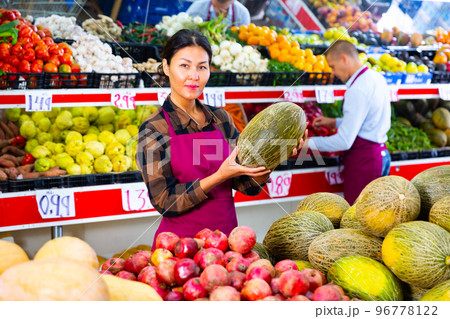 Smiling saleswoman offering ripe melon at farmers market 96778122