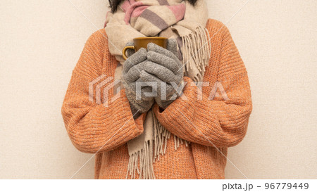 セーターとマフラーと手袋を身につける冬服の女性｜マグカップを持つ女性 96779449