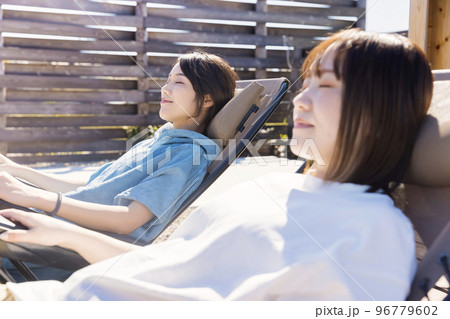 屋外サウナの前で外気浴をする2人のサウナ女子 96779602