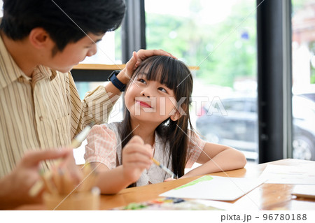 Happy proud Asian dad and daughter having fun together, drawing and painting watercolor 96780188