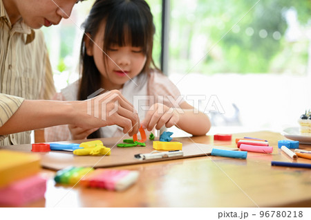 Happy Asian dad and daughter enjoys moulding colorful clay or play dough together at home 96780218