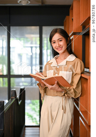 Portrait, Asian female in a library or bookstore, smiling and looking at the camera 96780786