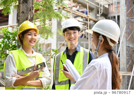 Female architect having a conversation with two engineers in the construction site. 96780917