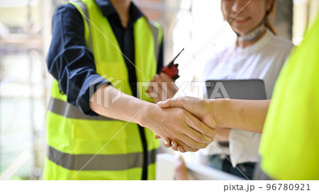 close-up, Male engineer shaking hands with a businessman in the construction site. 96780921