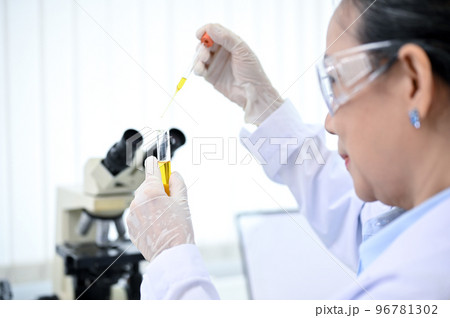 Professional-aged Asian female chemist dropping a chemical liquid into a test tube 96781302