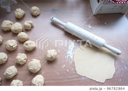 Hands knead thick dough, roll out with a rolling pin on the kitchen table, decorated with festive decorations for Christmas and New year. Baking at home, aroma and comfort. 96782864