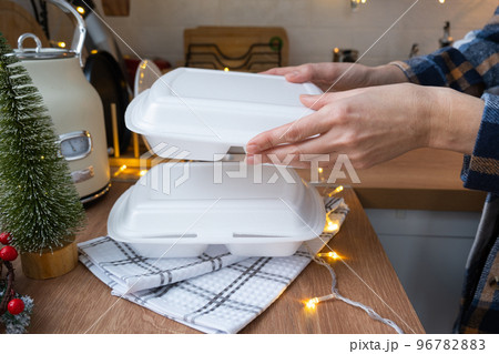 Food delivery service containers on table white scandi festive kitchen in christmas decor. Eve New year, saving time, too lazy to cook, hot order, disposable plastic box in fairy light. mock up 96782883