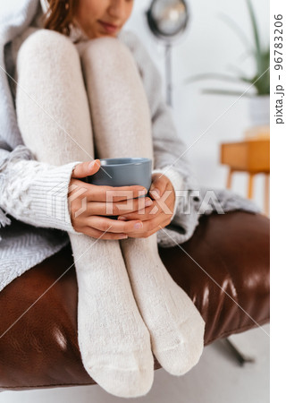 Cropped shot of woman sitting holding a mug at feet Cropped shot of woman sitting holding a mug at feet 96783206