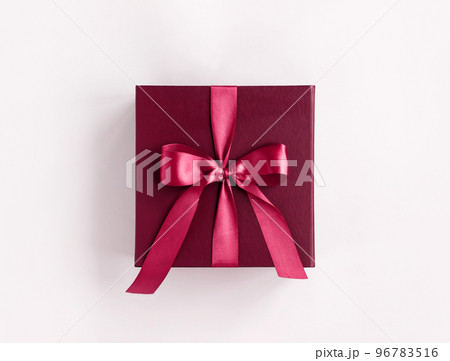 Magenta colored gift box with a purple bow made of satin on soft white background. Color of the year. St Valentines day, Birthday, New Year, Christmas presents concept. 2023 Xmas symbol 96783516