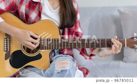 Close up fingers playing guitar strings, Strum to make a sound, Acoustic guitar, Catching guitar chords to create music, Music therapy and meditation practice with playing the guitar. 96785011