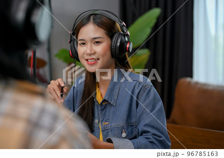Confident Asian female radio host is recording her podcast and interviewing her guest 96785163
