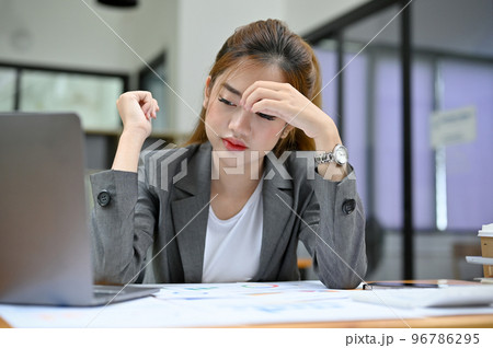Stressed and tired Asian businesswoman suffering from headache or overworked. 96786295