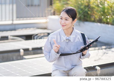 ソーラーパネルを点検する若い女性の作業員 96788325