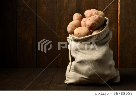 a sack full of potatoes on dark wooden background a sack full of potatoes on dark wooden background 96788955