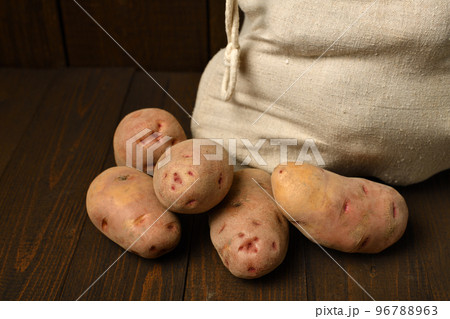 a sack full of potatoes on dark wooden background a sack full of potatoes on dark wooden background 96788963
