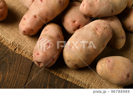 a pile of potatoes on burlap on a dark wood background a pile of potatoes on burlap on a dark wood background 96788989