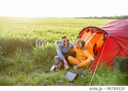 Young couple at campsite with tent on green field 96789320