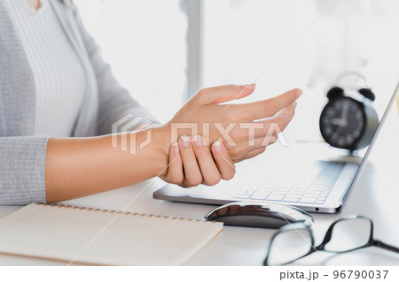 Closeup woman holding her hand pain from using laptop computer long time. Office syndrome concept. Closeup woman holding her hand pain from using laptop computer long time. Office syndrome concept. 96790037