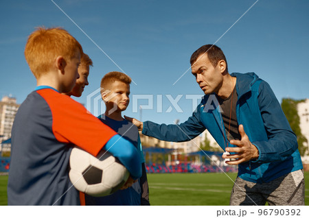 Confident soccer coach encouraging young football team Confident soccer coach encouraging young football team 96790392