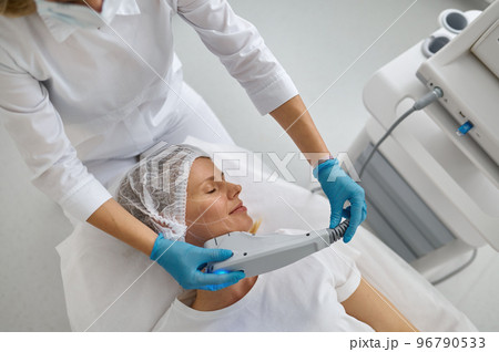 Cosmetologist applying laser to facial hair remove 96790533