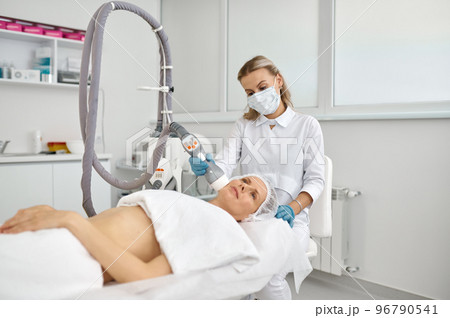 Doctor cosmetologist doing face apparatus massage Doctor cosmetologist doing face apparatus massage 96790541