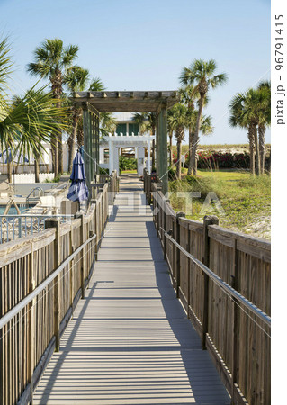 Destin, Florida- Pathway with wooden handrails with pergola roofs 96791415