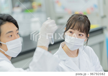 大学の研究室で試験管を見ながら会話をする男女 96792082