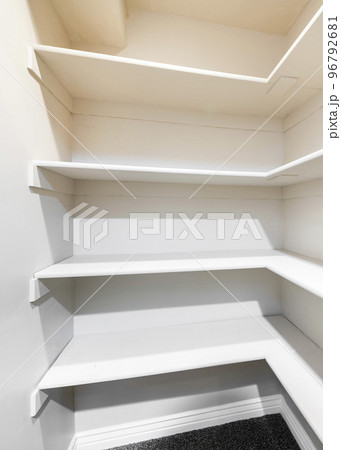 Vertical White linen closet with wall mounted shelves and carpeted floor 96792681