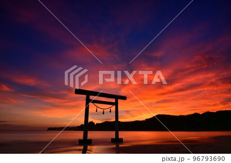 真っ赤な夕焼けに染まる海に立つ鳥居 96793690