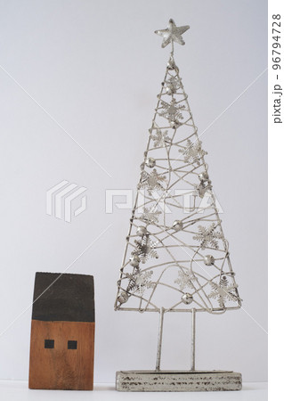 銀色の素材で作られた雪の結晶で飾られたクリスマスツリーと木で作られた家のインテリア 96794728