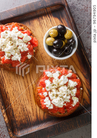 Dakos or Ntakos traditional Greek starter made of dried bread with tomato feta, oregano and olive oil closeup on the wooden board. Vertical top view 96794905