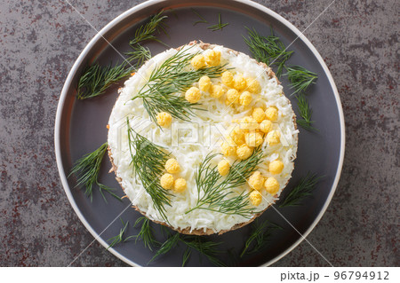 Tasty layered salad with saury, onion, potatoes, carrot, cheese, eggs and mayonnaise closeup on the plate. Horizontal top view Tasty layered salad with saury, onion, potatoes, carrot, cheese, eggs and mayonnaise closeup on the plate. Horizontal top view 96794912