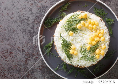Layered salad mimosa with canned saury, potatoes, cheese, carrots and eggs closeup on the plate. Horizontal top view Layered salad mimosa with canned saury, potatoes, cheese, carrots and eggs closeup on the plate. Horizontal top view 96794913