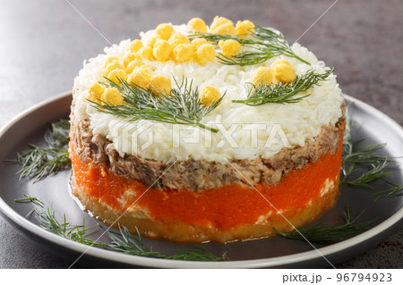 Festive Russian salad Mimosa with canned saury, potatoes, cheese, carrots and eggs closeup on the plate. Horizontal Festive Russian salad Mimosa with canned saury, potatoes, cheese, carrots and eggs closeup on the plate. Horizontal 96794923