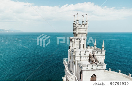 Crimea Swallow's Nest Castle on the rock over the Black Sea. It is a tourist attraction of Crimea. Amazing aerial view of the Crimea coast with the castle above abyss on sunny day. Crimea Swallow's Nest Castle on the rock over the Black Sea. It is a tourist attraction of Crimea. Amazing aerial view of the Crimea coast with the castle above abyss on sunny day. 96795939