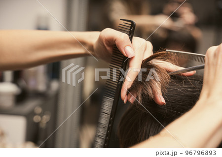 Hairstylist does cutting hair tips of a female customer in a beauty salon. Womens fashion and style 96796893