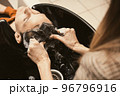 Young man getting a modern haircut. Hair salon master washing client hair at barber shop. Men's 96796916
