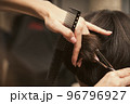 Hairstylist does cutting hair tips of a female customer in a beauty salon. Womens fashion and style 96796927