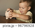 Child extract coins from piggy bank. Smart happy boy saving money in a piggy bank, learning about 96796928