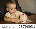Child dollar banknote piggy bank in the table. Smart happy boy saving money in a piggy bank 96796931